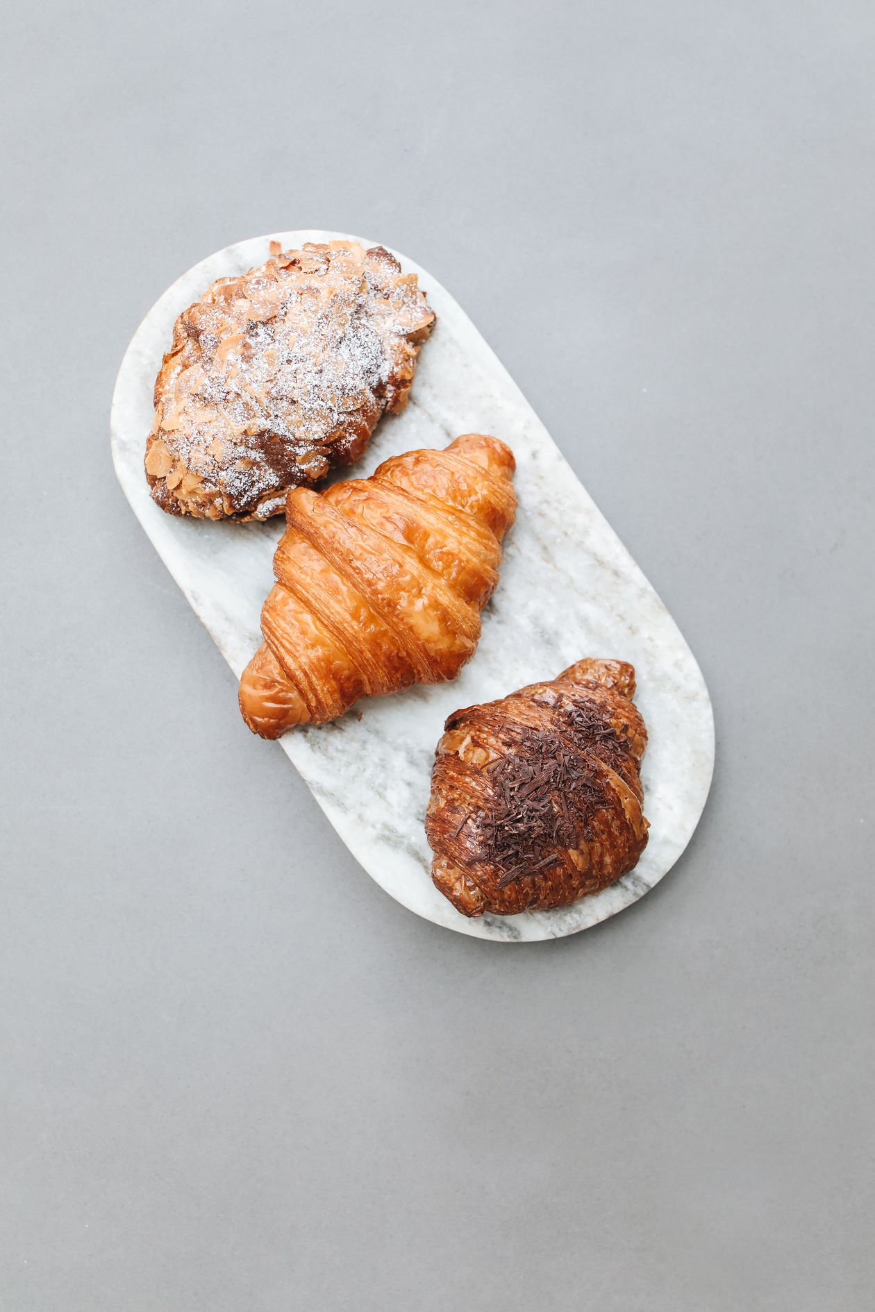 Croissants et viennoiseries dorées sur un plateau en marbre clair, vus de dessus